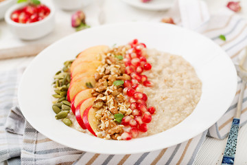 Tasty and healthy oatmeal porridge with apples, pomegranate and nuts. Healthy breakfast. Fitness food. Proper nutrition