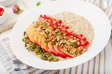 Tasty and healthy oatmeal porridge with apples, pomegranate and nuts. Healthy breakfast. Fitness food. Proper nutrition