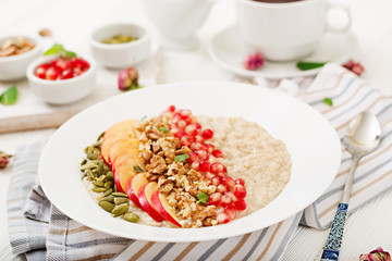 Tasty and healthy oatmeal porridge with apples, pomegranate and nuts. Healthy breakfast. Fitness food. Proper nutrition