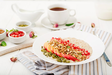 Tasty and healthy oatmeal porridge with apples, pomegranate and nuts. Healthy breakfast. Fitness food. Proper nutrition