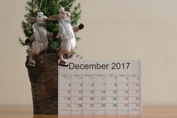Close-up: calendar of December 2017 is next to a festive decoration from a small Christmas tree and a cute sports couple of hares on skates. Preparation for Christmas and New Year's holidays.