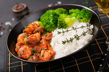 Pieces of chicken fillet with mushrooms stewed in tomato sauce with boiled broccoli and rice. Proper nutrition. Healthy lifestyle. Dietetic menu.