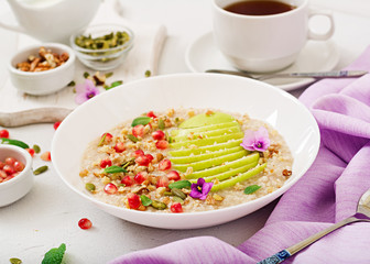 Tasty and healthy oatmeal porridge with apples, pomegranate and nuts. Healthy breakfast. Fitness food. Proper nutrition