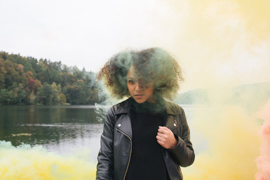 Young woman with colored smoke bombs