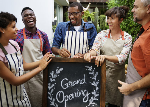 Group of diverse people with store grand opening board