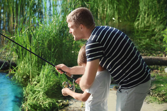 Father with son fishing from riverside