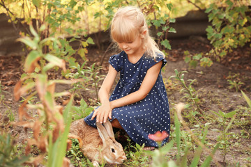 Little girl with adorable rabbit in garden