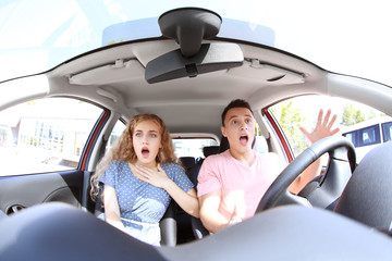 Frightened young couple sitting in car