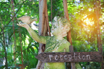 Old Baby statue with bird in the garden with reception label for decoration in European style against green leaf wall background.