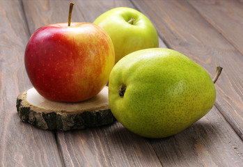 Ripe green pear and red-yellow apples on a wooden table. Rustic style.