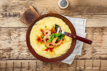 Plate with fresh tasty shrimp and grits on wooden table, top view