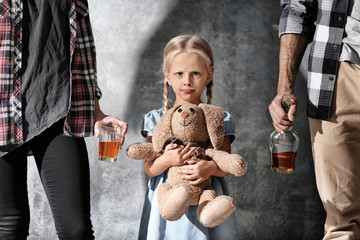 Little girl with toy rabbit and parents with alcoholic drink on grey background