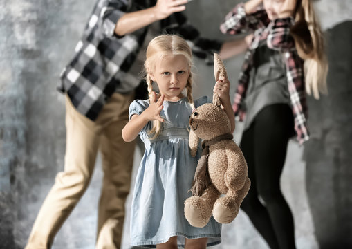 Little girl with toy rabbit and man abusing woman on grey background