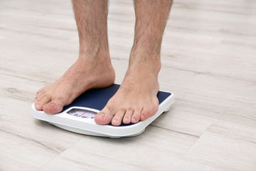 Overweight man measuring his weight using scales on floor