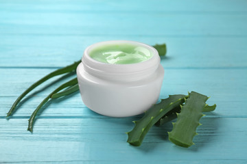 Jar with body cream and aloe on color wooden background