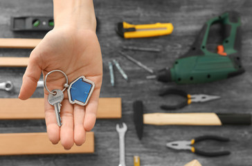 Fototapeta premium Real estate agent holding key with trinket on blurred background