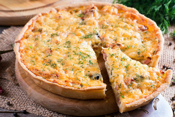 Sliced quiche with cheese and bacon on wooden background. Horizontal