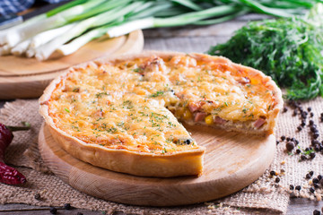 Traditional french quiche pie with with cheese and bacon on cutting board