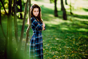 Fototapeta premium Fashion outdoor photo of beautiful young woman in elegant blue dress. Portrait of gorgeous long hair woman in checkered dress posing outdoors. Copy space