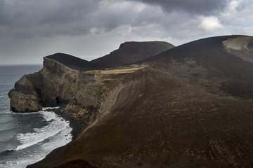 a lava reef above the turbulent sea on the volcanic faial island of the Azores