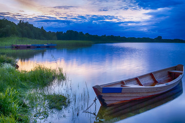 Travel Destinations Concepts. Tranquil and Peaceful Picturesque Landscape of The Strusto Lake with Wooden Boat at Foreground. Lake is a Part of National Braslav Lakes Reserve.