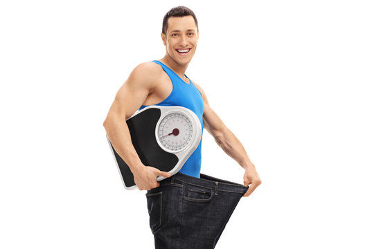 Guy in an oversized pair of jeans holding a weight scale
