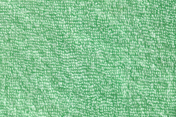 The towel is green. Texture of cotton fibers.