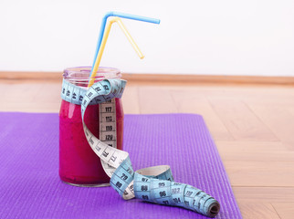 Smoothie and measuring tape on yoga mat