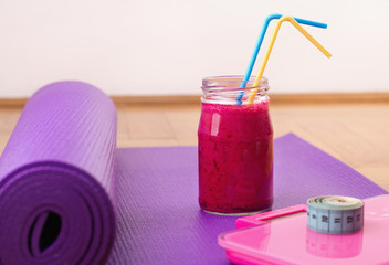 Smoothie, scale and measuring tape on yoga mat