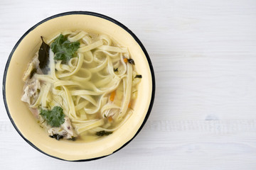 Appetizing chicken soup with noodles, with the addition of potatoes, carrot greens and bay leaf.