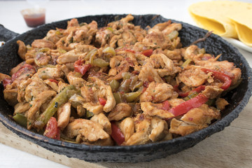 Chicken stew with red and green pepper, with red onion, pickled cucumber and spices in a frying pan.