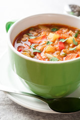 Italian minestrone soup in bowl on gray stone background