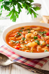 Italian minestrone soup on white wooden background.