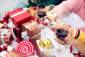 Hands of people celebrating New year party in home with wine drinking glasses. New year and Christmas party concept. Happiness and Friendship concept. Relation and Funny together theme. Clinking glass