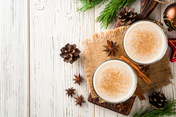 Homemade eggnog with grated nutmeg and cinnamon on white wooden table. Traditional Christmas drink.