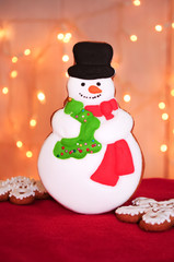 Christmas gingerbread snowman and snowflakes on a red velvet with light garlands. Concept of new year gift. Picture for a confectionery catalog. Invitation or greeting card with copy space.