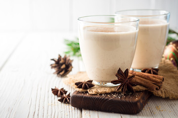 Homemade eggnog with grated nutmeg and cinnamon on white wooden table. Traditional Christmas drink.