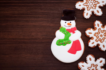 Christmas gingerbread snowman and snowflakes on a dark table. Concept of new year gift. Picture for a confectionery catalog. Invitation or greeting card with copy space.
