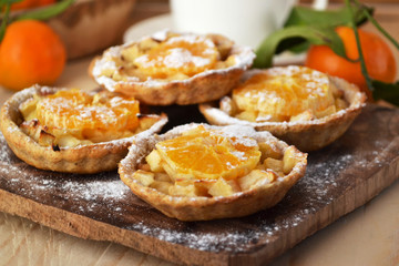 Obraz na płótnie Canvas Homemade fruit tarts with caramelized apple and tangerine. Whole grain flour pastry. Dietary baked goods