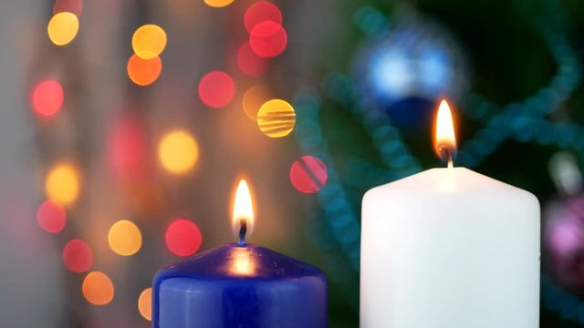 Put out fire on white and blue candles over holiday bokeh blinking background and Christmas tree