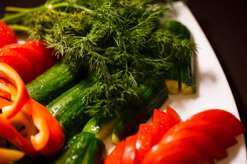 plate with different fresh vegetables tomatoes,cucumbers,pepper and greens. organic food