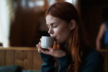 Beautiful young woman drinks coffee in a cafe