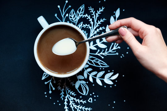 piece of cake and a cup of coffee on a black background decorated painted white snowflake.