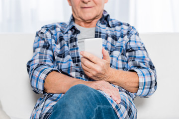 cropped shot of senior man wit smartphone at home