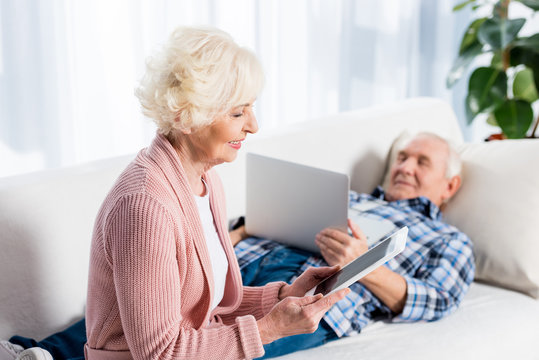 selective focus of senior wife and husband using digital devices at home