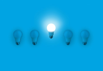 Blue light bulbs with glowing one different idea on blue background. minimal concept. top view. New...