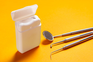 Dental floss and instruments on yellow background