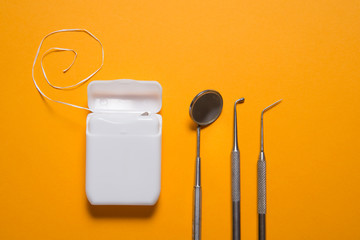 Dental floss and instruments on yellow background