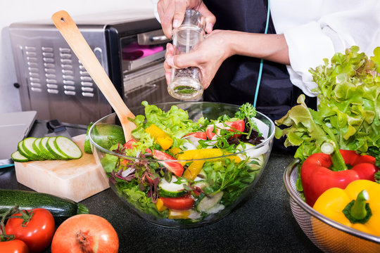 Healthy Woman makes fresh vegetable salad with olive oil, tomato and salad.