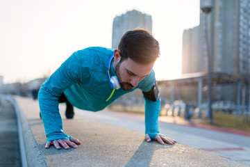 Young handsome man doing push ups outdoors